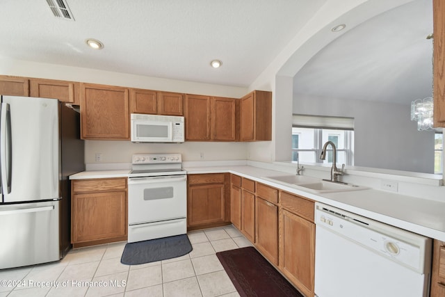 kitchen with pendant lighting, white appliances, sink, vaulted ceiling, and light tile patterned floors