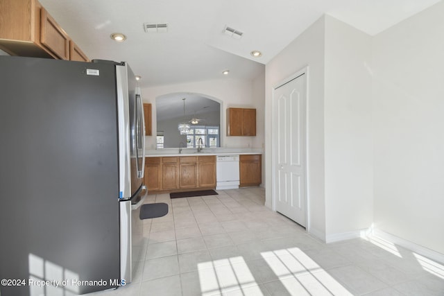 kitchen with pendant lighting, white dishwasher, vaulted ceiling, light tile patterned floors, and stainless steel refrigerator