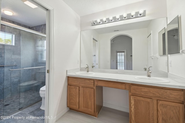 bathroom featuring a textured ceiling, vanity, toilet, and a wealth of natural light