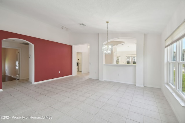 unfurnished living room with a chandelier and light tile patterned flooring