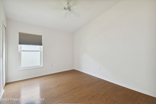 empty room with hardwood / wood-style floors, ceiling fan, and vaulted ceiling