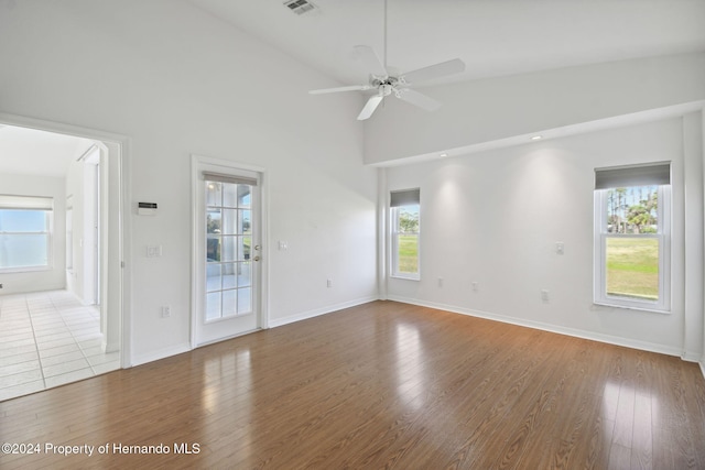 empty room featuring ceiling fan, high vaulted ceiling, and hardwood / wood-style flooring