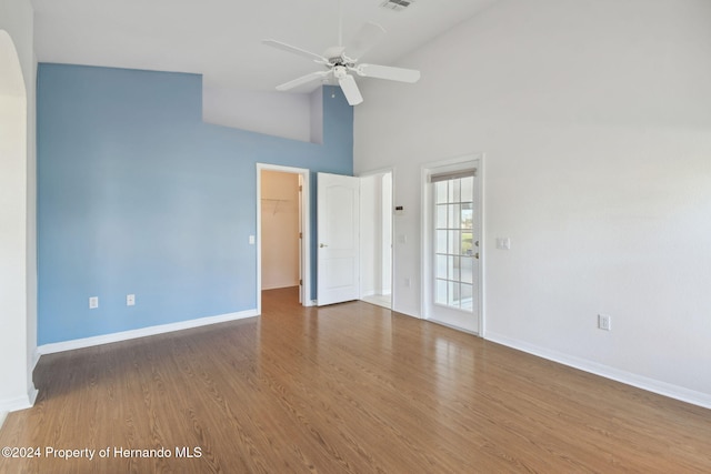 empty room with wood-type flooring, high vaulted ceiling, and ceiling fan