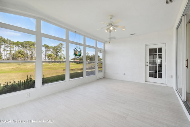 unfurnished sunroom featuring ceiling fan and a wealth of natural light