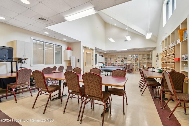 dining room with a drop ceiling and a towering ceiling