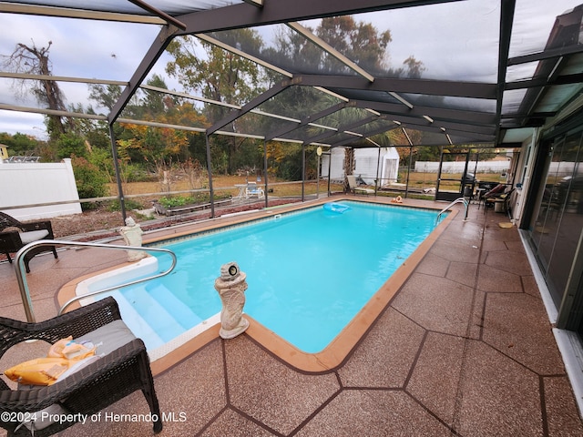 view of swimming pool with a patio area, a storage unit, and a lanai