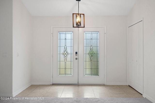 entryway featuring a notable chandelier, light tile patterned flooring, and french doors