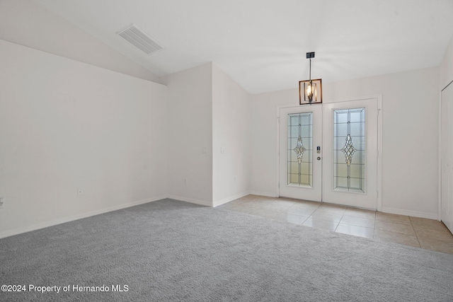 carpeted spare room featuring an inviting chandelier, french doors, and vaulted ceiling