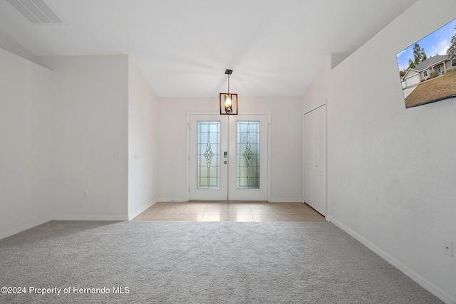 foyer with light carpet, french doors, and an inviting chandelier