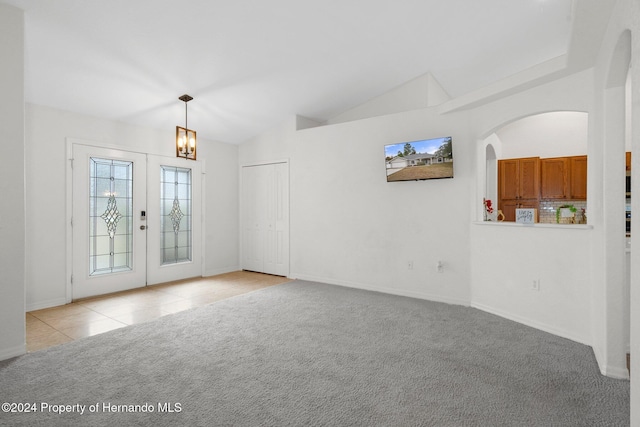 spare room featuring a notable chandelier, french doors, light carpet, and vaulted ceiling