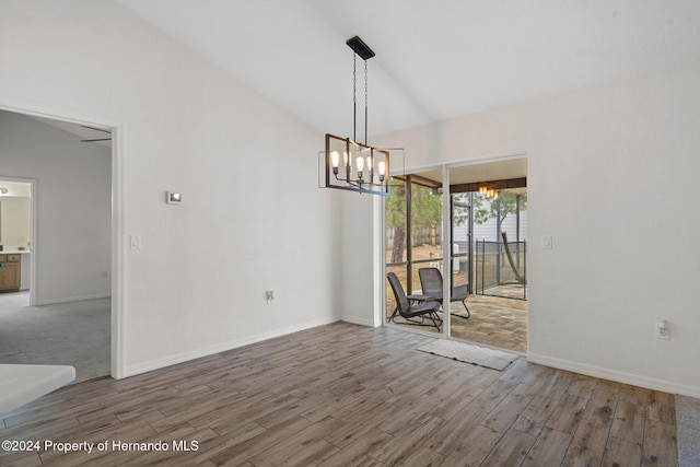 unfurnished dining area with an inviting chandelier, hardwood / wood-style flooring, and vaulted ceiling