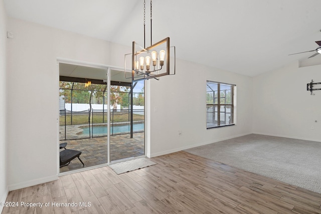 unfurnished dining area featuring carpet and ceiling fan with notable chandelier