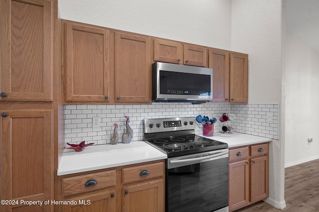 kitchen featuring stainless steel appliances, light hardwood / wood-style flooring, and tasteful backsplash