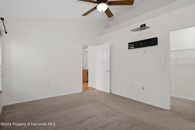 unfurnished bedroom featuring ceiling fan, a walk in closet, light carpet, and a closet