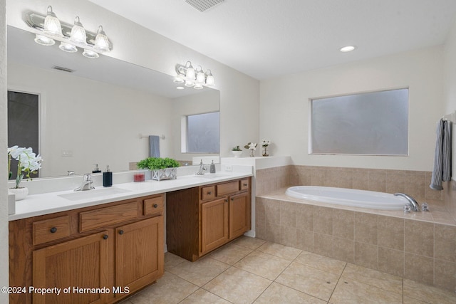 bathroom featuring tile patterned flooring, vanity, and a relaxing tiled tub