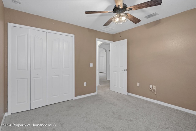 unfurnished bedroom with ceiling fan, a closet, and light carpet