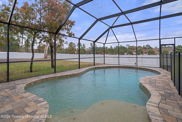 view of swimming pool featuring a patio area, a lanai, and a lawn