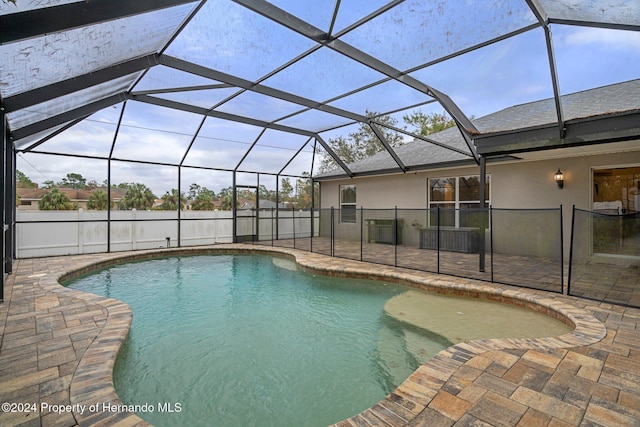 view of swimming pool featuring glass enclosure and a patio area