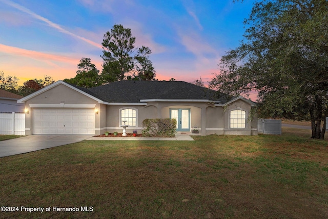 single story home with a lawn, french doors, and a garage