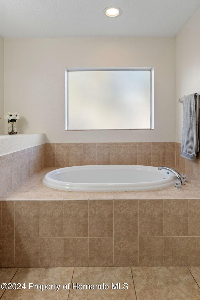 bathroom with tile patterned floors and tiled bath