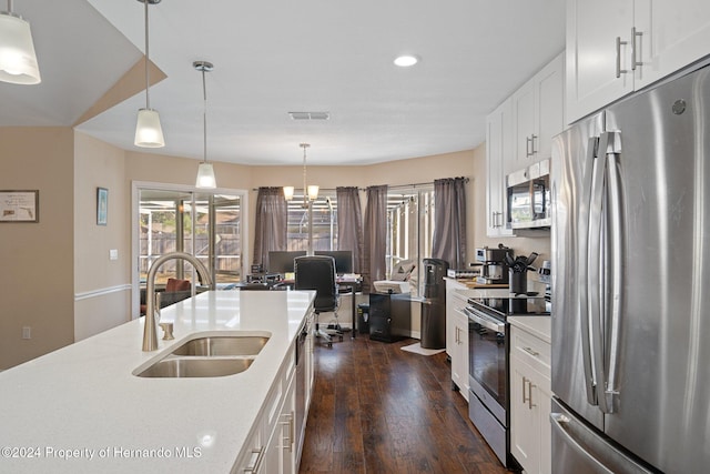 kitchen featuring white cabinetry, sink, dark wood-type flooring, hanging light fixtures, and appliances with stainless steel finishes