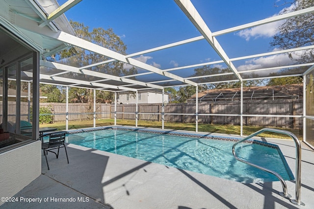 view of pool with glass enclosure, a patio area, and a lawn