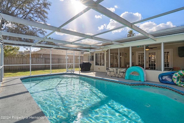 view of pool featuring glass enclosure, a patio area, and grilling area