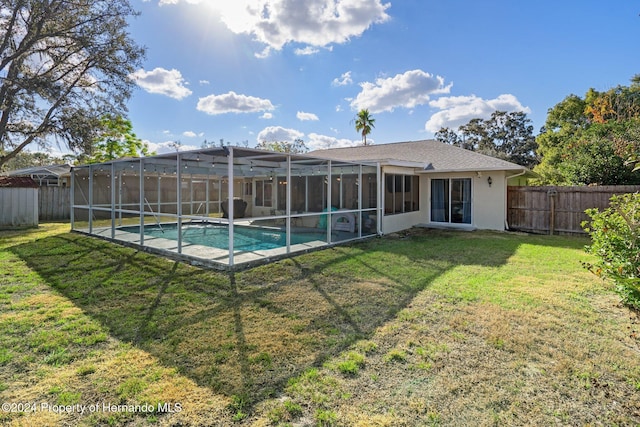 rear view of house with a lawn, a lanai, and a fenced in pool