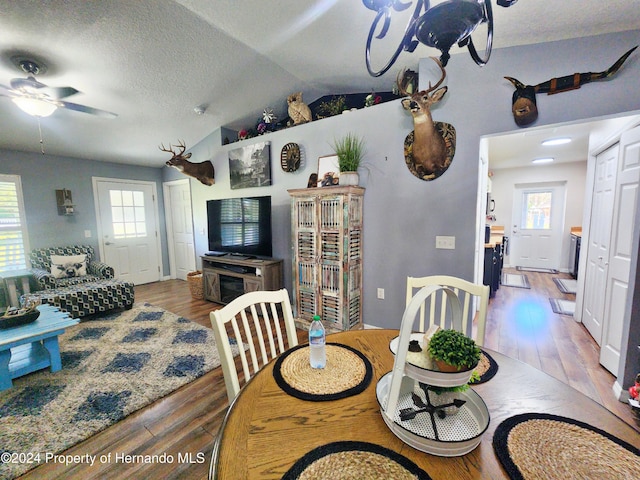 dining space featuring a healthy amount of sunlight, wood-type flooring, lofted ceiling, and a textured ceiling