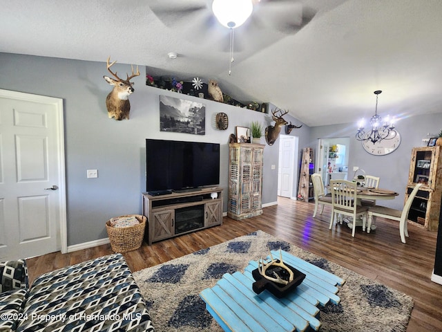 living room featuring ceiling fan with notable chandelier, dark hardwood / wood-style floors, and vaulted ceiling