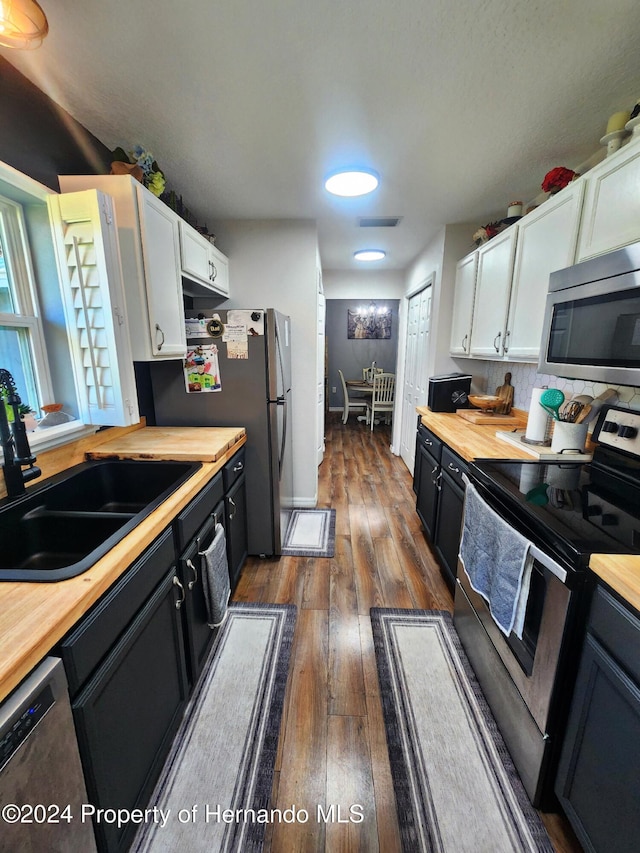 kitchen with dark hardwood / wood-style flooring, stainless steel appliances, sink, white cabinets, and butcher block counters