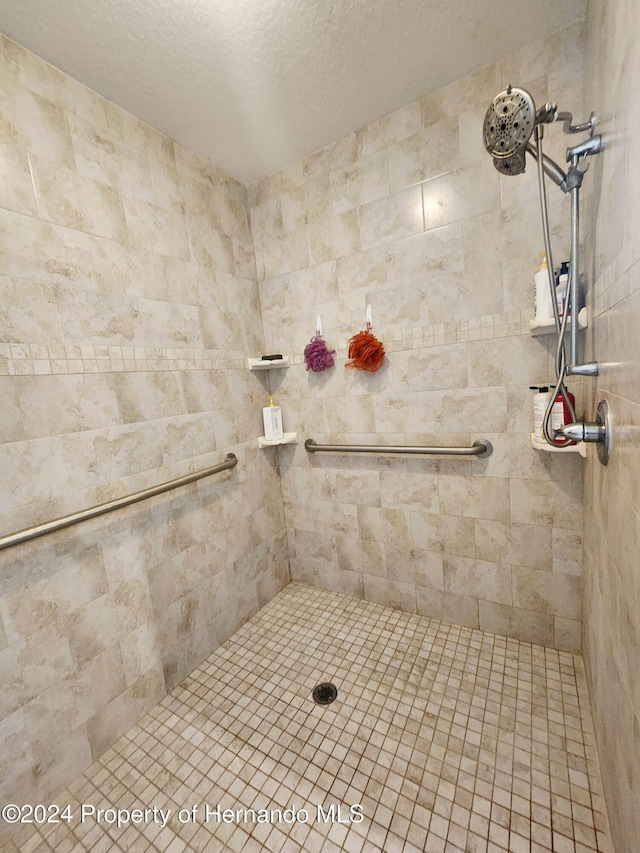 bathroom with tiled shower and a textured ceiling