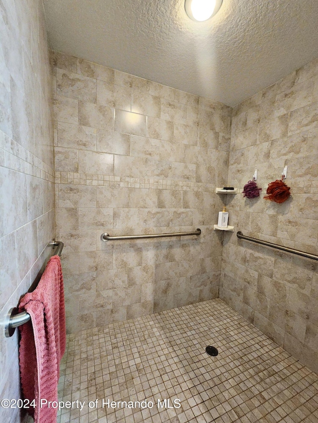 bathroom with a tile shower and a textured ceiling