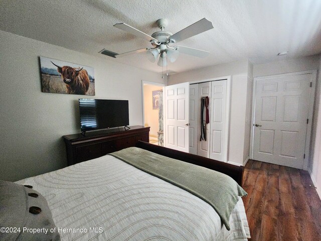 bedroom featuring a textured ceiling, ceiling fan, dark wood-type flooring, and a closet