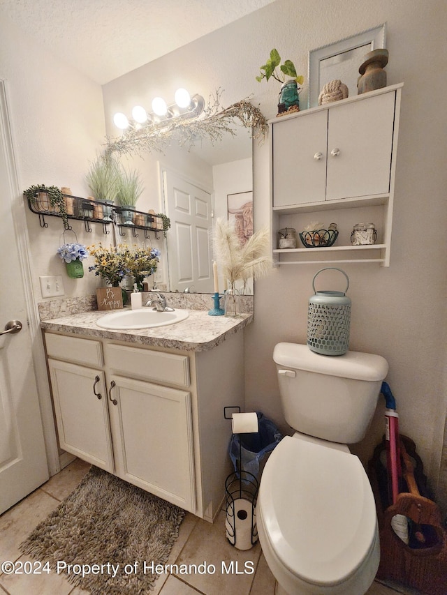 bathroom with tile patterned flooring, a textured ceiling, vanity, and toilet