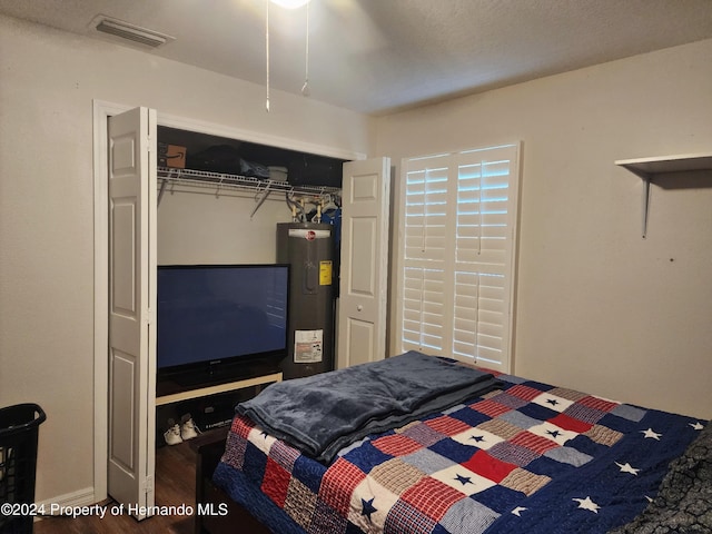 bedroom featuring electric water heater, a closet, and hardwood / wood-style flooring