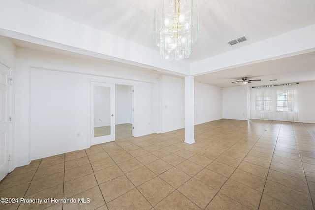 spare room with ceiling fan with notable chandelier and light tile patterned floors