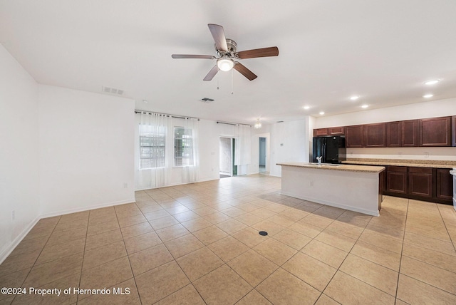 kitchen featuring black fridge, ceiling fan, a kitchen island, and light tile patterned flooring