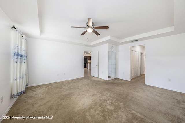 carpeted empty room featuring a raised ceiling and ceiling fan