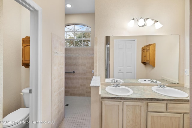 bathroom with tile patterned floors, vanity, toilet, and a tile shower