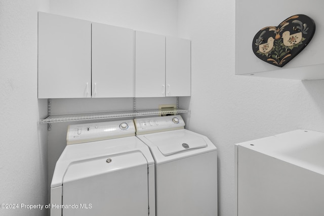 clothes washing area with cabinets and separate washer and dryer