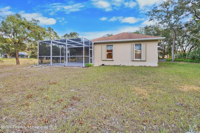 rear view of house featuring a lanai and a lawn