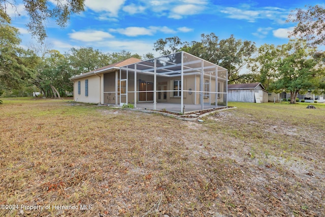 back of property with a yard, glass enclosure, and a patio area