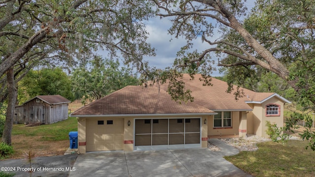 ranch-style home with a storage unit, a garage, and a front lawn