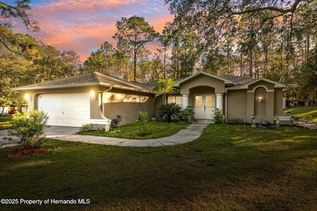 single story home featuring a lawn and a garage