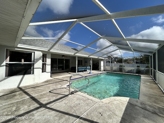 view of pool featuring outdoor lounge area, ceiling fan, a patio, and glass enclosure