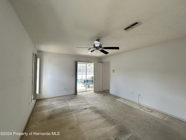 carpeted empty room featuring ceiling fan and a textured ceiling