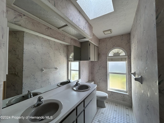 bathroom featuring a skylight, tile patterned floors, a textured ceiling, toilet, and vanity