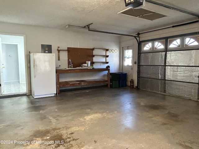 garage featuring electric panel, white fridge, and a garage door opener