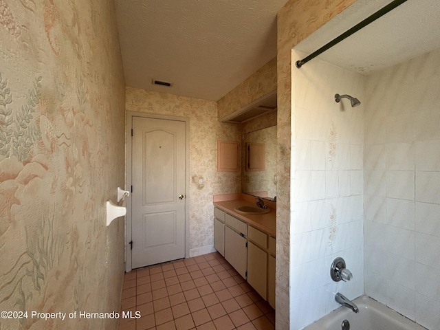 bathroom with vanity, a textured ceiling, tiled shower / bath combo, and tile patterned floors